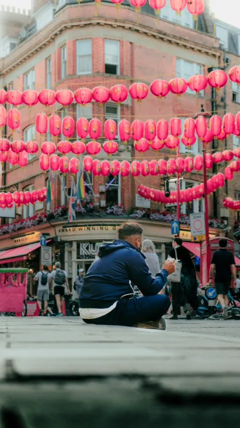 Homme assis au milieu de la rue sous les lanternes de Chinatown, Londres